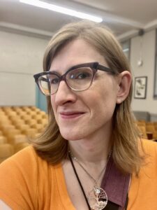 Woman with blonde hair, glasses and a yellow sweater